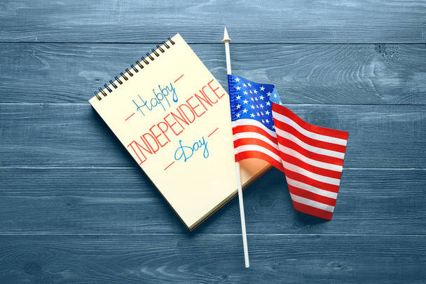 Notebook met tekst Happy Independence Day en USA vlag op kleur houten achtergrond - Foto, afbeelding
