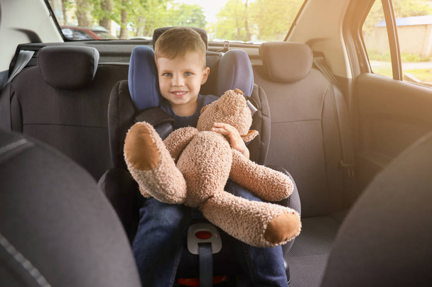 おもちゃのクマを持つ小さな男の子は、車の座席に座ってバックル - 写真・画像