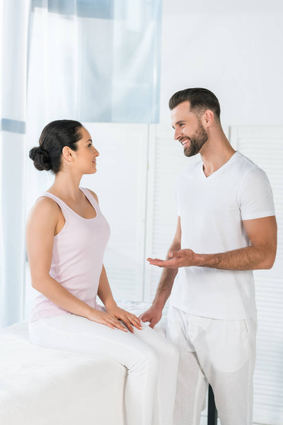 cheerful masseur gesturing while looking at attractive woman  - Foto, Imagem