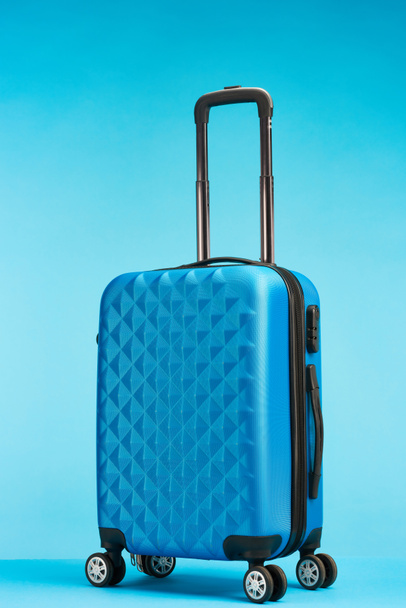 blue suitcase with handle on wheels on blue background - Photo, Image