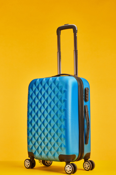 borsa da viaggio in plastica blu con manico su ruote isolato su arancione
 - Foto, immagini