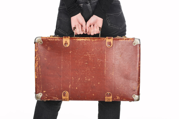 partial view of woman in jeans holding vintage leather suitcase isolated on white - Valokuva, kuva