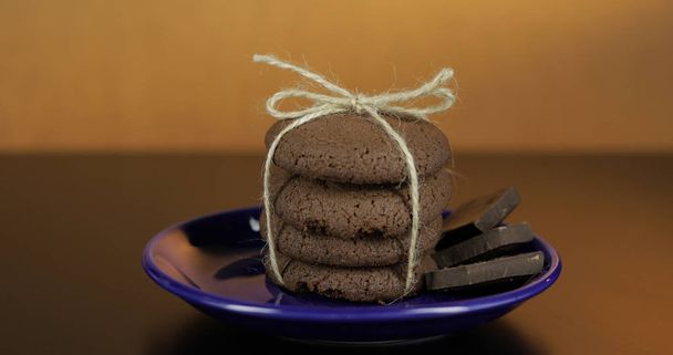 Lecker aussehender Schokoladenkeks auf einem blauen Teller auf dunkler Oberfläche. Warmer Hintergrund - Foto, Bild