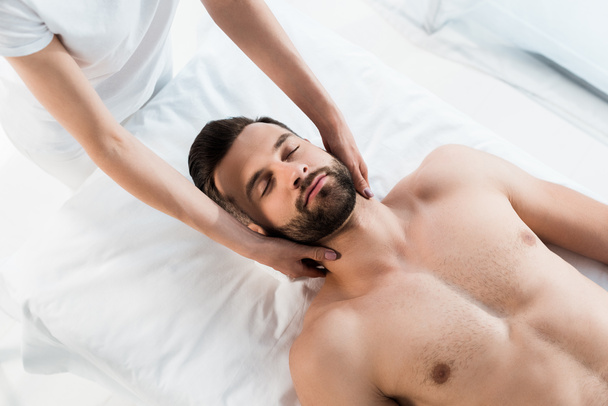 recortado vista de masajista haciendo masaje de cuello a hombre guapo con los ojos cerrados
 - Foto, imagen