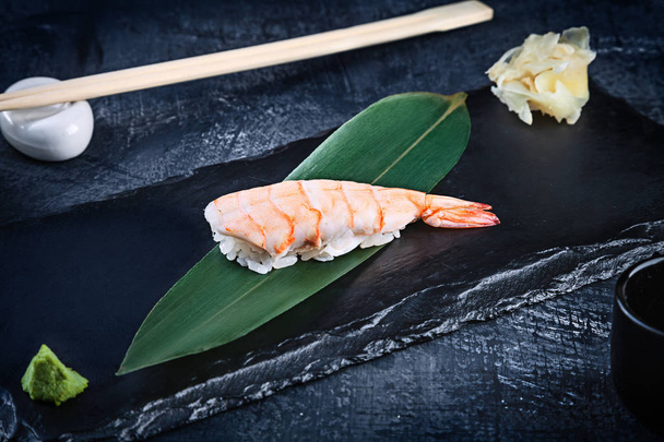 Close up view on served Nigiri with shrimp on dark plate on dark background with copy space. Delicious Ama Ebi Shrimp Nigiri Sushi. Traditional Japanese cuisine - Foto, Imagen