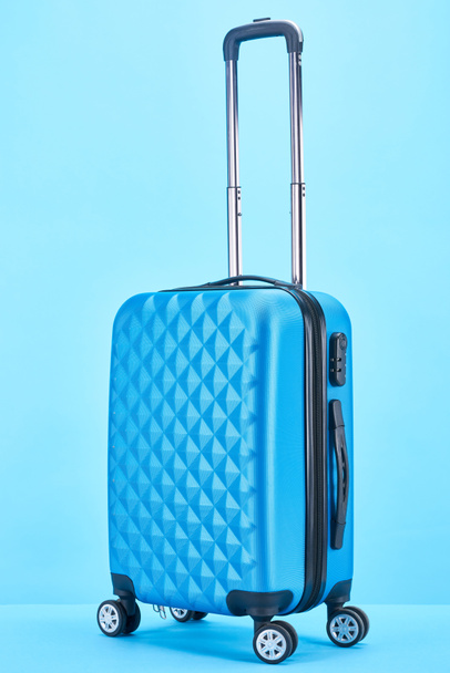 blue colorful suitcase with handle on wheels on blue background - 写真・画像