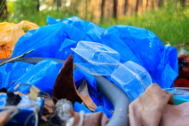 Pakiet plastikowych śmieci znajduje się w lesie na leśnej drodze, zanieczyszczenia z natury, śmieci i - Zdjęcie, obraz
