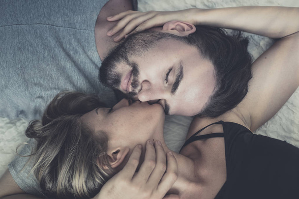 Loving happy couple in love smile and kiss her cheek on the bed, - Fotografie, Obrázek