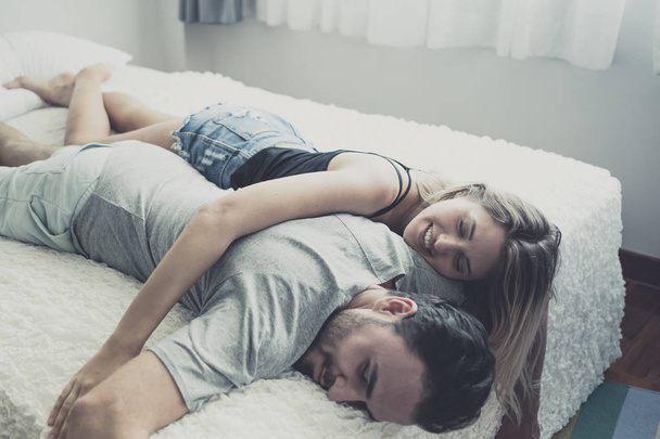 Liefdevolle gelukkig paar in liefde glimlach en knuffel elkaar op het bed, - Foto, afbeelding