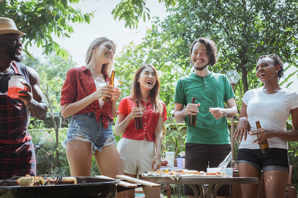 Ομάδα ευτυχών φίλων που στέκονται τρώγοντας και πίνοντας μπύρες στο μπαρ - Φωτογραφία, εικόνα