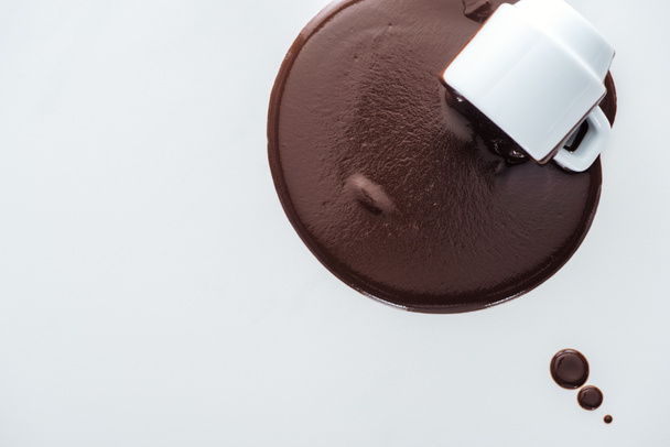 Top view of cup with spilling chocolate and chocolate drops on white background  - Fotó, kép