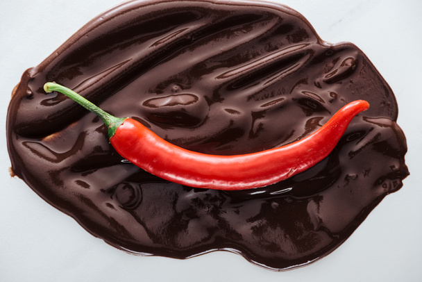 Top view of chili with melted dark chocolate on white background - Photo, Image