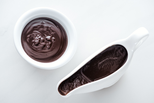 Vista superior de cuenco y bote de salsa lleno de chocolate negro derretido
 - Foto, Imagen