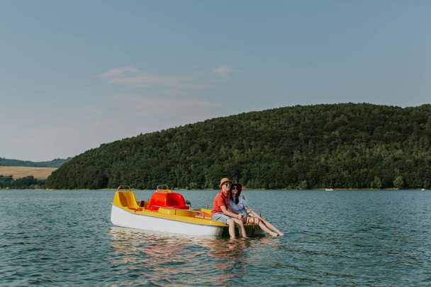 Закохана пара відпочиває на педальному човні з ногами у воді
. - Фото, зображення