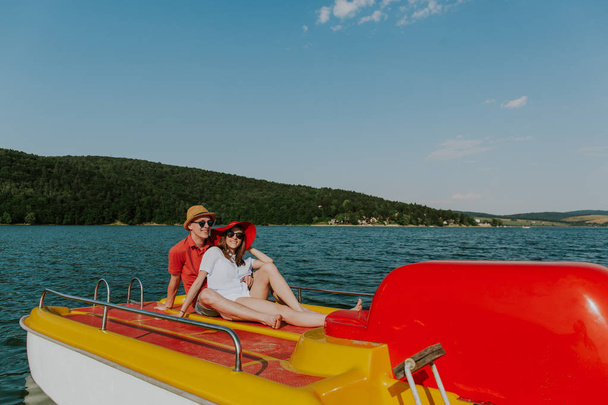Wesoły mężczyzna i kobieta bawią się łodzią na jeziorze. - Zdjęcie, obraz