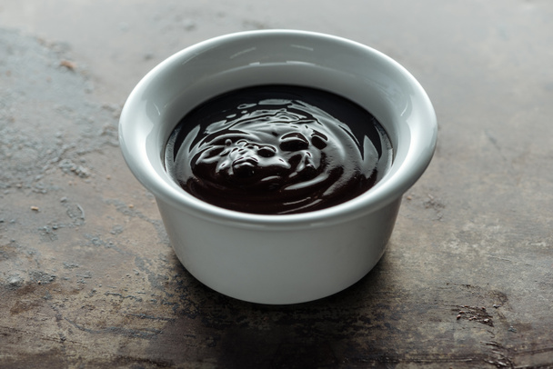 High angle view of bowl with melted chocolate on rust metal background - Photo, Image