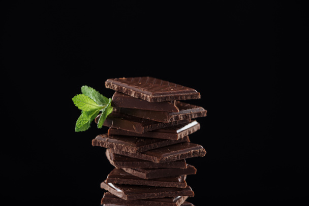 Dark pieces of chocolate with fresh mint, isolated on black - Photo, Image