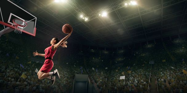 Female basketball player makes slam dunk. Basketball player on big professional arena during the game - Photo, Image