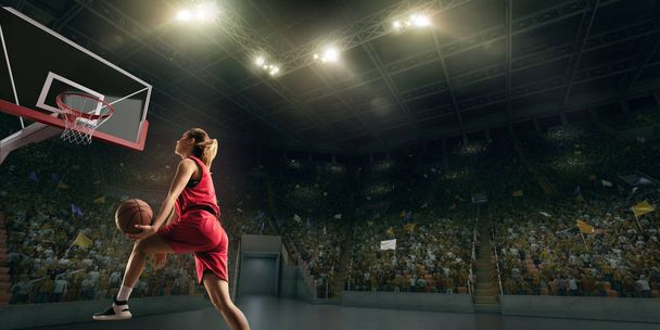 Ο θηλυκός παίχτης του μπάσκετ κάνει πάταγο. Παίκτης μπάσκετ στο μεγάλο επαγγελματικό αρένα κατά τη διάρκεια του παιχνιδιού - Φωτογραφία, εικόνα