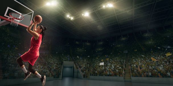 Женщина-баскетболистка делает слэм данк. Баскетболист на большой профессиональной арене во время игры
 - Фото, изображение