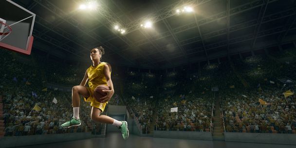 Женщина-баскетболистка делает слэм данк. Баскетболист на большой профессиональной арене во время игры
 - Фото, изображение