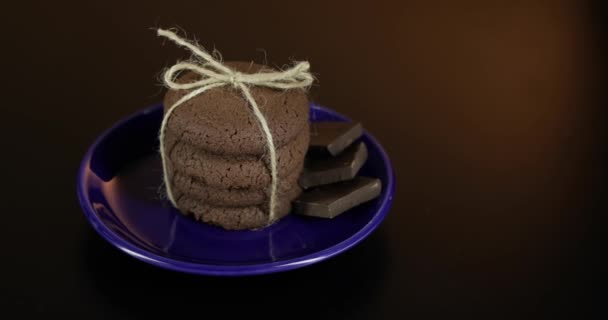Koyu yüzeyde mavi bir tabak üzerinde lezzetli görünümlü çikolatalı kurabiye. Sıcak arka plan - Video, Çekim