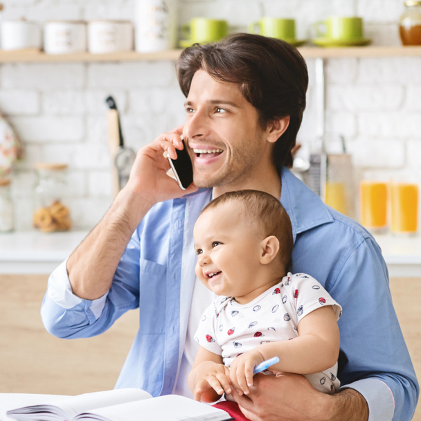 Junger Mann telefoniert zu Hause im Büro und kümmert sich um Baby - Foto, Bild