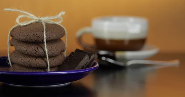 Νόστιμο φαίνεται μπισκότο σοκολάτας σε ένα μπλε πιάτο στη σκοτεινή επιφάνεια. Θερμό φόντο - Πλάνα, βίντεο