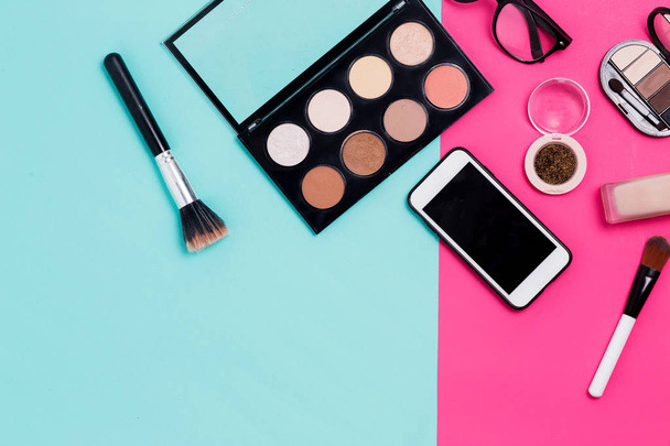 Face concealer, nail Polish, brush, Foundation, eyeshadow and glitter and smartphone - Foto, imagen