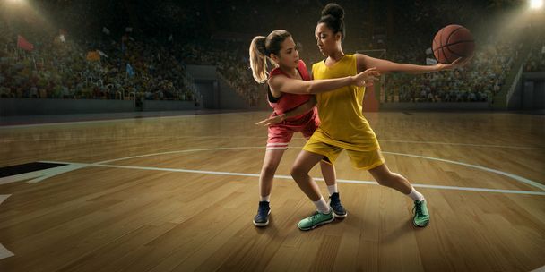 Женщины-баскетболистки сражаются за мяч. Баскетболисты на большой профессиональной арене во время игры
 - Фото, изображение