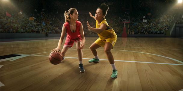 Naispuoliset koripalloilijat taistelevat pallosta. Koripalloilijat isolla ammattilaisareenalla pelin aikana
 - Valokuva, kuva