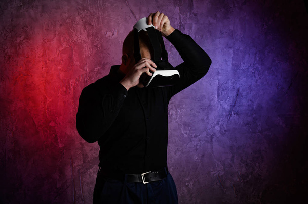 Brutal man wearing virtual reality goggles in studio. Using with VR headset. - Fotó, kép
