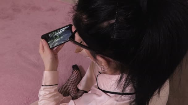 Kobieta informująca o uzyskaniu wiadomości wideo na smartfonie - Materiał filmowy, wideo