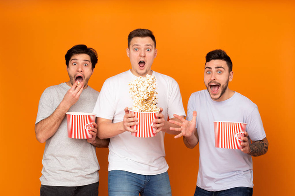 Homens chocados comendo pipocas e assistindo filme assustador
 - Foto, Imagem