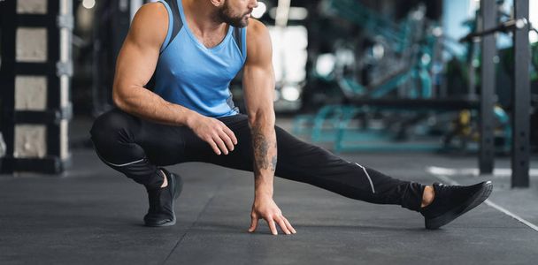 Чоловік розтягує ногу перед тренуванням у спортзалі
 - Фото, зображення
