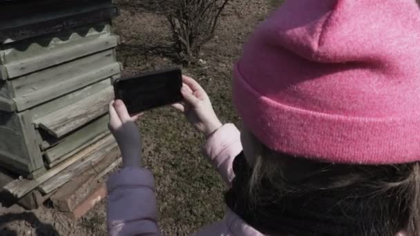 Chica usando smartphone cerca de colmena de abejas
 - Metraje, vídeo