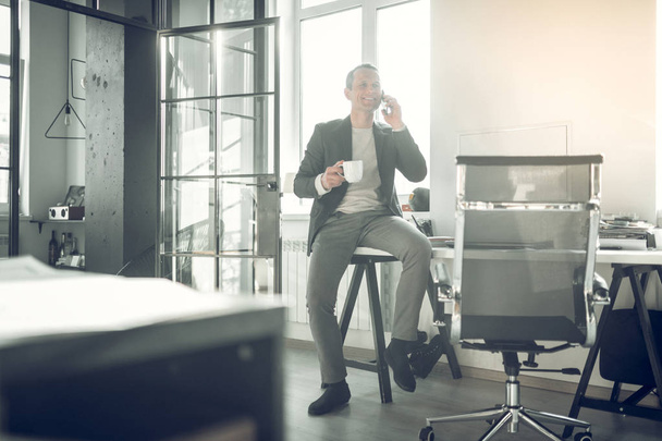 Stylish businessman sitting on table and calling his business partner - Foto, Imagem