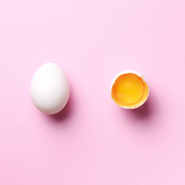 Food concept with broken egg and whole one on pink background. Top view. Creative pattern in minimal style. Flat lay. Square crop - Photo, Image