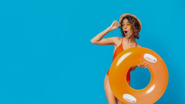 Amazed black woman with inflatable ring looking at copy space - Фото, зображення
