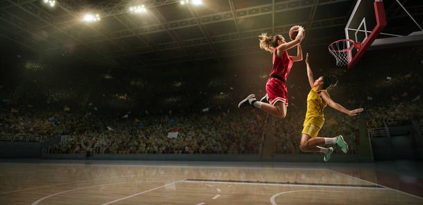 Las jugadoras pelean por el balón. Jugador de baloncesto hace slam dunk en gran arena profesional durante el juego
 - Foto, imagen