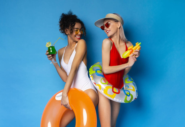 різноманітні подруги в купальнику насолоджуючись коктейлем і грою водяний пістолет
 - Фото, зображення