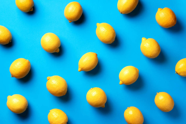 Food pattern with lemons on blue paper background. Top view. Summer concept. Vegan and vegetarian diet - Фото, зображення