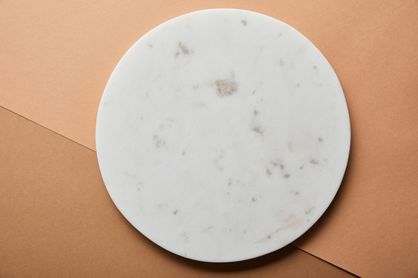top view of grey marble circle on beige and brown paper background - Fotó, kép
