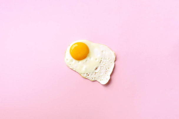 One fried egg on pink paper background. Creative food concept in minimal style. Top view - Fotoğraf, Görsel