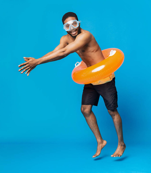 Cheerful black shirtless man in swim goggles and inflatable ring - Photo, Image