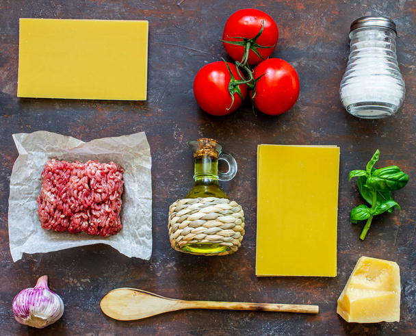 Lasagna, tomatoes, minced meat and other ingredients. Dark background. Italian cuisine. - Zdjęcie, obraz