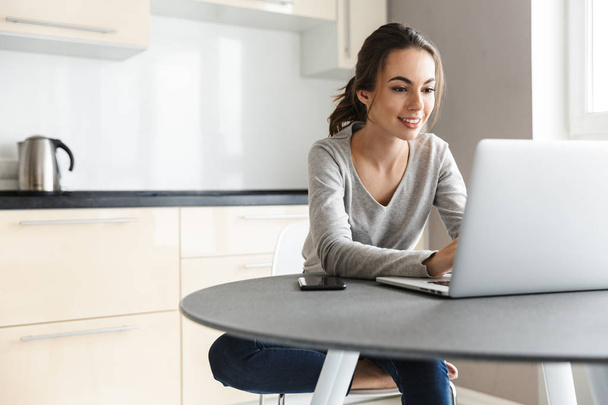 Attractive smiling young woman working on laptop - Foto, Bild