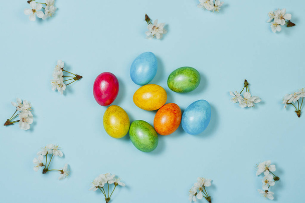 Easter eggs and spring flowers on a blue background. Concept of celebrating Easter. Flat lay, top view - Photo, Image