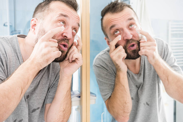 Man applying moisturizer cream in bathroom - Foto, Imagem