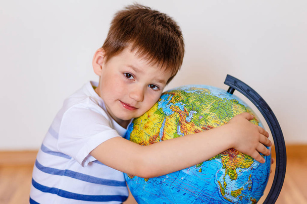 five-year-old child embracing large globe - Fotó, kép